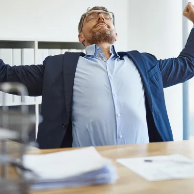 A man stretching at his desk.