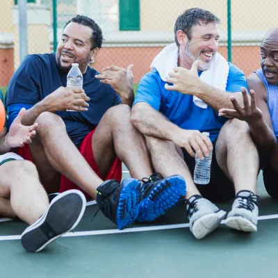 A group of men resting on the sidelines during a game of basketball.