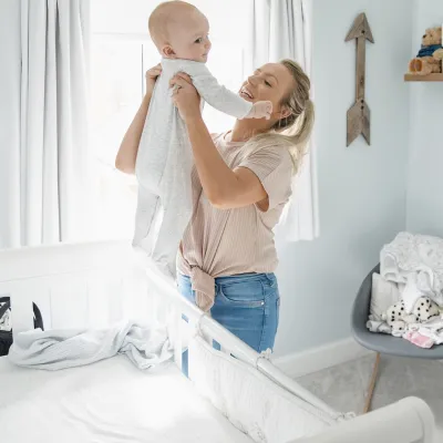 A mom lifts her infant out of the crib.