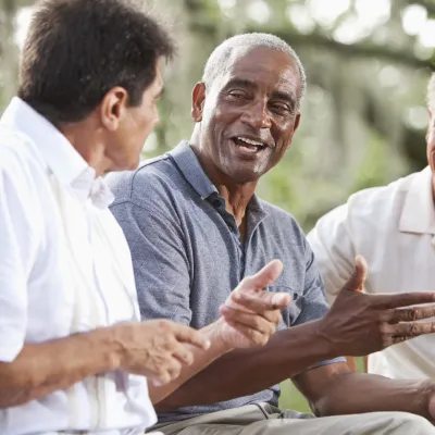 Three men have a conversation outdoors.