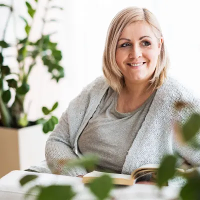 A woman looking at something while reading a book