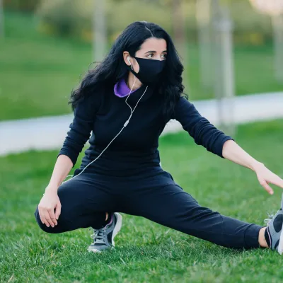 A woman stretching outdoors in the grass.