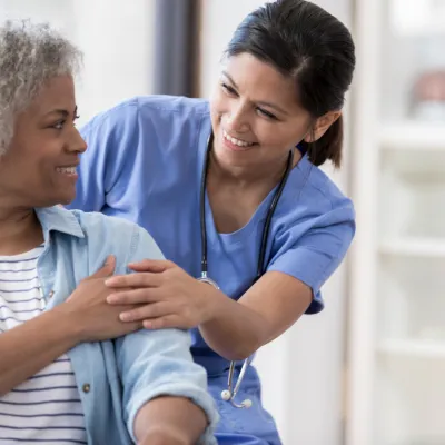 A woman speaks with her nurse after a medical procedure.