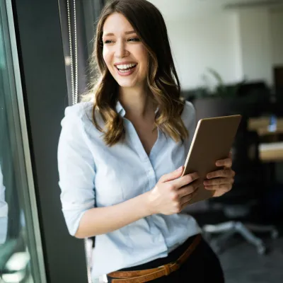An adult woman smiling next to a window