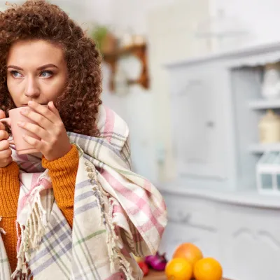 A woman sipping on her cup of coffee in her kitchen