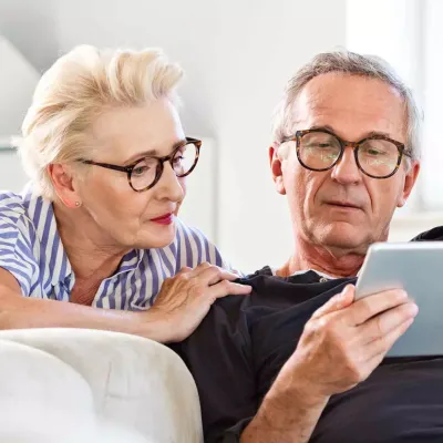An older couple reading on a tablet.
