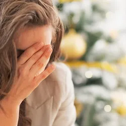 A stressed woman puts her hand over her eyes.
