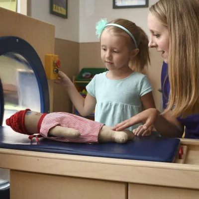 An imaging technician shows a child what to expect during an MRI.