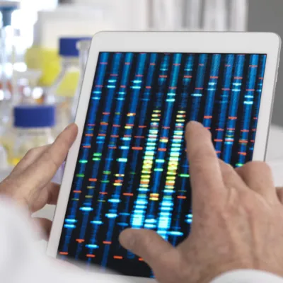 Scientist using an iPad with genomics graphic on screen.