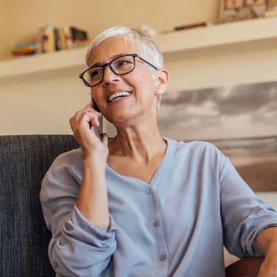White-haired woman seated and on phone