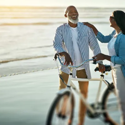 Couple smiling with bicycle on beach