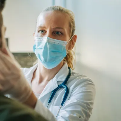 Masked physician examining patient.