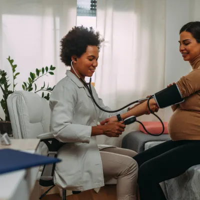 Pregnant woman getting her blood pressure checked by a physician
