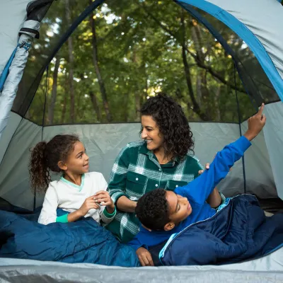 A mother camping his her two kids in the forest.