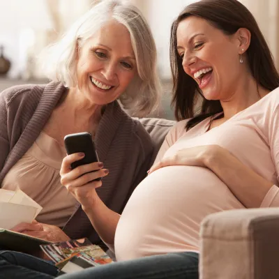Pregnant Woman Looking at Photos on a Cell Phone with her Mom.
