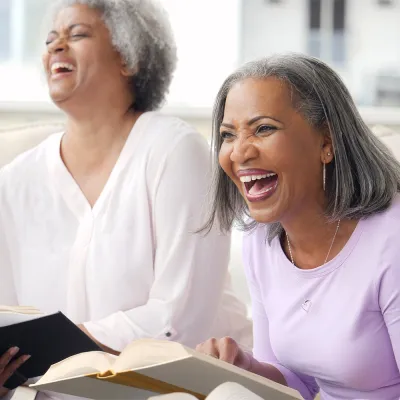 A group of older adults laughing while in a Bible study together.