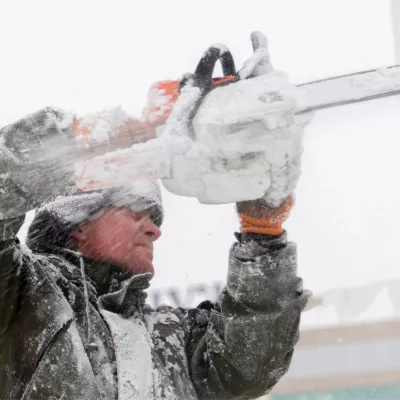A man using a chainsaw to cut ice.