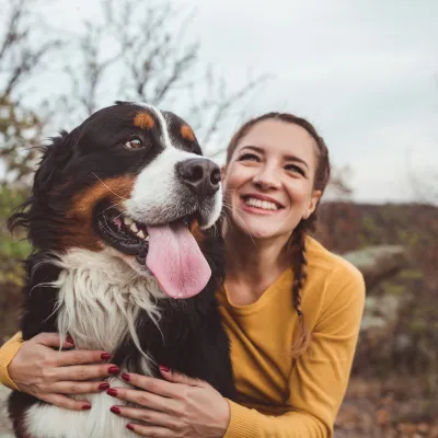 Woman smiling with bernese mountain dog while outside.