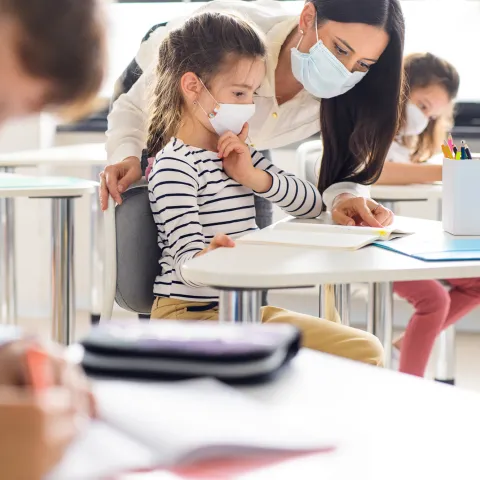 An elementary girl getting help with her assignment from her teacher