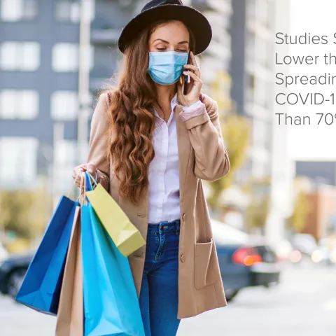 Woman walking outdoors while carrying shopping bags and talking on the phone.