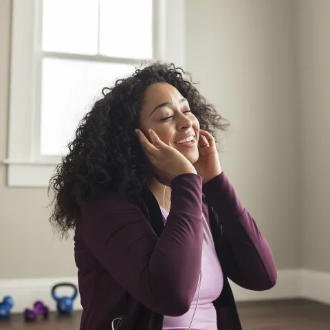 A young African American woman enjoys her music through her earbuds. 