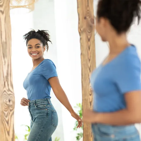 A young female adult looking at herself in the mirror