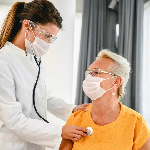 A doctor listens to a patient's breathing with a stethoscope 