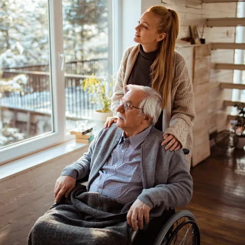 Caregiver Looks Out the Window with a Senior Patient at the Newly Fallen Snow.