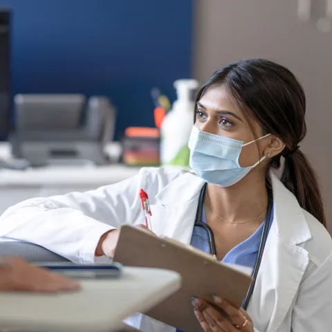 A Doctor Speaks to Her Patient on Her Level in an Exam Room.