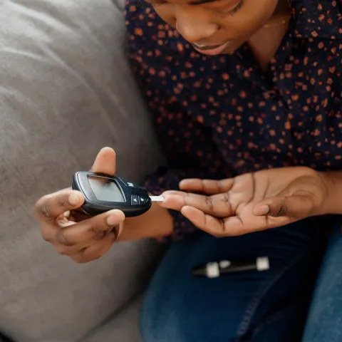 A Woman Tests Her Blood Sugar with a Finger Prick Glucose Device