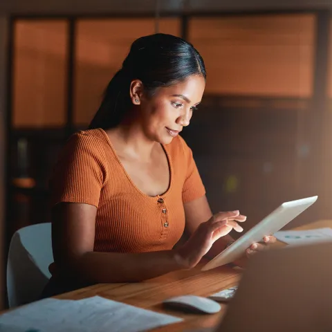 A Woman Surfs the Internet on a Table in a Dark Room of Her Home.