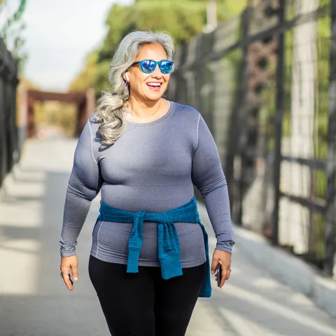 A Woman Walks Across a Pedestrian Bridge in the Fall