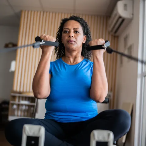 A Woman Exercises with Weight Machine in Her Home