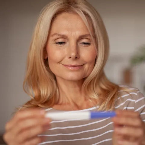 A Woman Smiles as She Looks at a Pregnancy Test