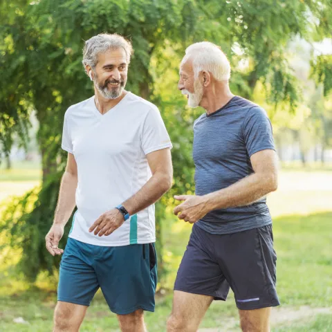 Two Senior Men Walk Through a Park While on a Jog