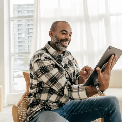 A Man Smiles During a Video Call on His Tablet in His Home.