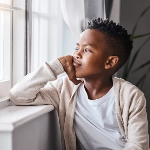 A Boy Stares Out the Window Bored in His Bedroom