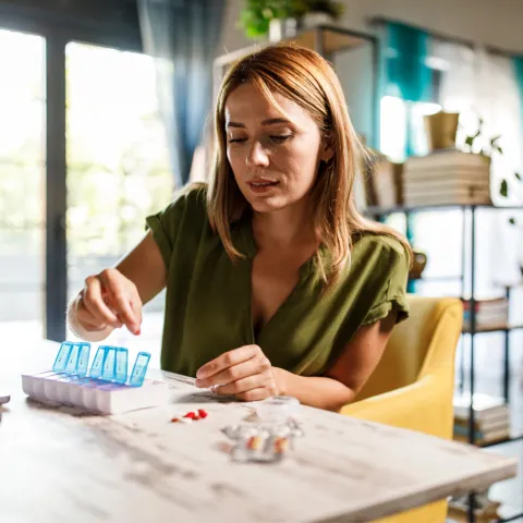 A Woman Fills Her Pill Box at Home.