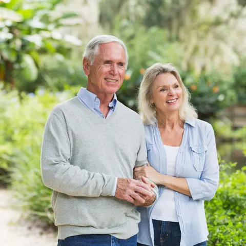 Senior Couple walking past several green shrubs and plants