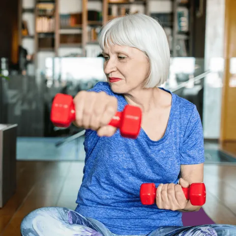 Senior woman doing strength training with weights.