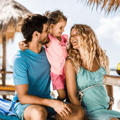 Family smiling at each other at beach.
