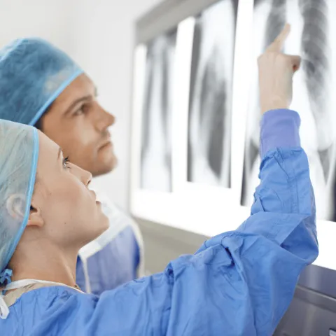 two doctors in scrubs examining a lung x-ray