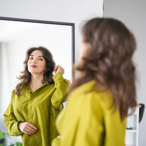 A woman looking at herself in the mirror.
