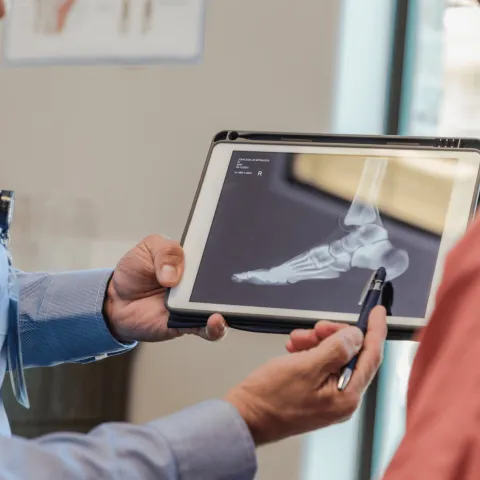 A doctor shows a patient an x-ray of a foot.