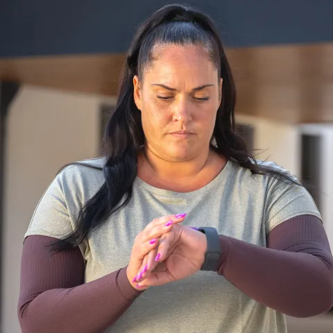 A woman checks her watch during exercise. 