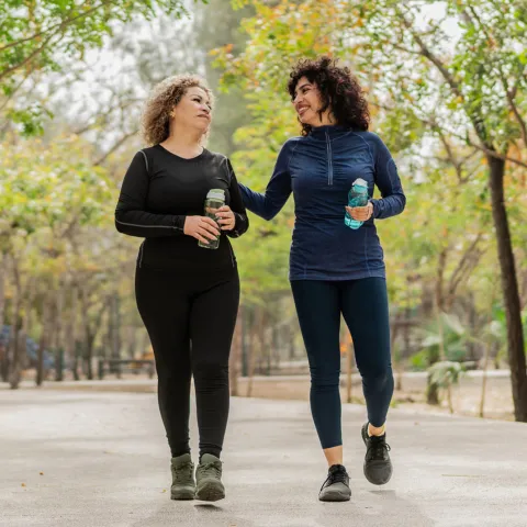 Two women walking on a trail outdoors.