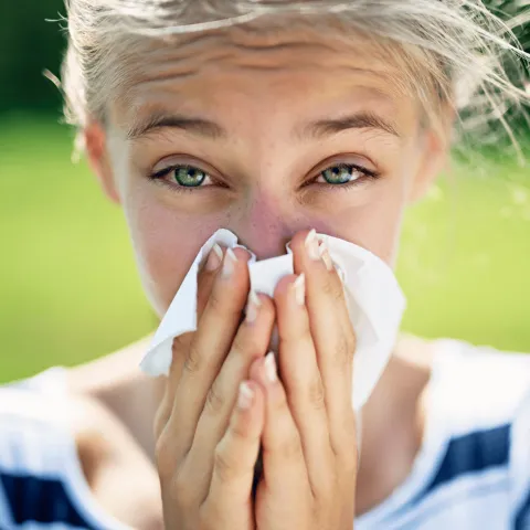 A Young Woman Blows Her Nose Out Side in a Garden