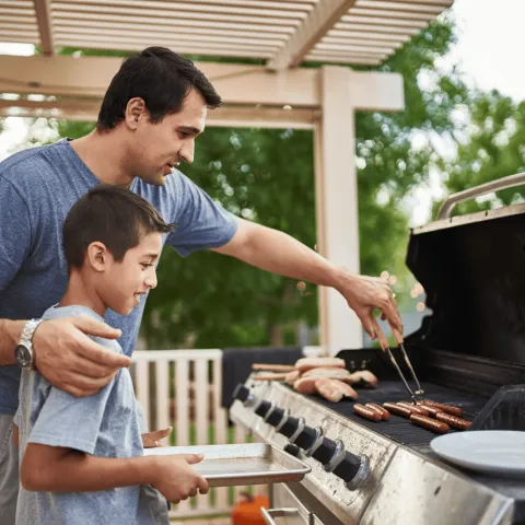 A Father Teaches His Son How to Use a Barbecue Grill