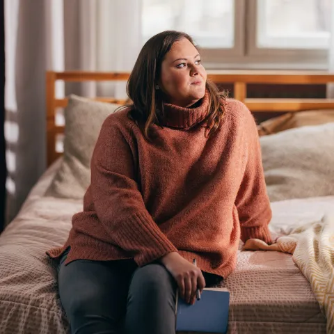 A woman sitting on her bed.