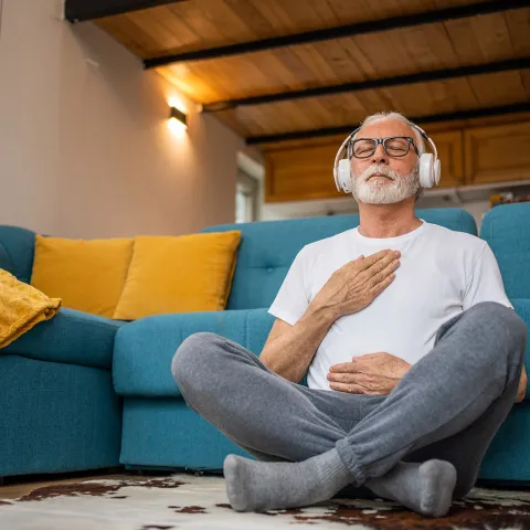 An older man meditating at home.